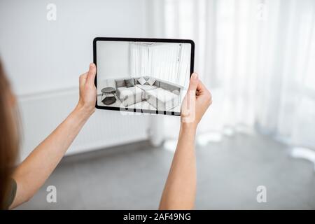 Neue Möbel auf einem digitalen Tablet in den leeren Innenraum, schauen, wie es aussieht, bevor Sie kaufen. Konzept der Augmented Reality in Design und Retail Business Stockfoto