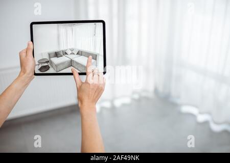 Neue Möbel auf einem digitalen Tablet in den leeren Innenraum, schauen, wie es aussieht, bevor Sie kaufen. Konzept der Augmented Reality in Design und Retail Business Stockfoto