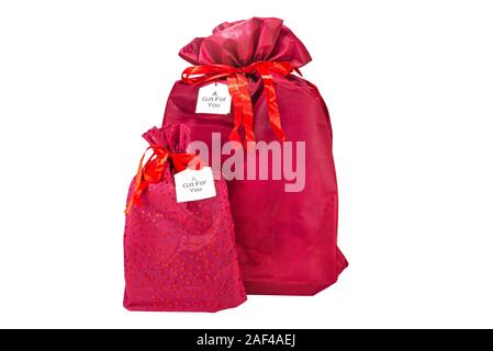 Zwei Weihnachtsgeschenke verpackt in ein Burgunder Stoff mit einer Schleife, mit der Aufschrift "ein Geschenk für Dich" auf ein Stück Papier, auf einem weißen Zurück isoliert Stockfoto