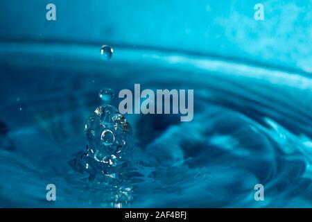 Wassertropfen spritzen in einem blauen Glas Stockfoto