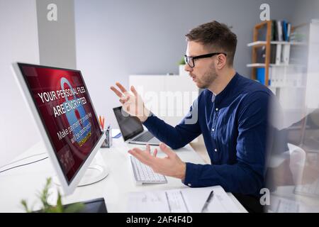 Besorgt Geschäftsmann am Computer mit Ransomware Wort auf dem Bildschirm am Arbeitsplatz Stockfoto