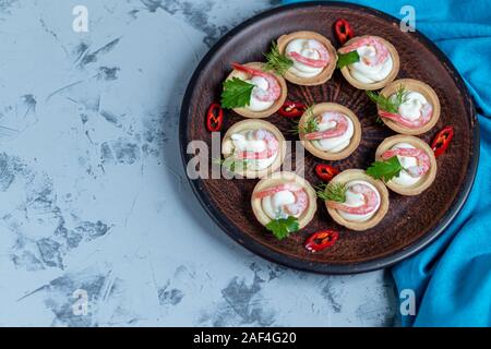 Törtchen mit Frischkäse und Garnelen. Mit Zweige Dill und Petersilie dekoriert. Fisch und Meeresfrüchte. Urlaub Gericht. Auf einem hellen Hintergrund. Kopieren Sie Platz. Stockfoto