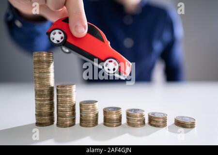 Nahaufnahme der Hand Fliegen einer Person Auto über Rückläufige gestapelte Münzen Stockfoto