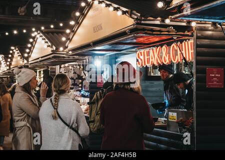 London, Großbritannien - 24 November, 2019: Die Menschen essen, von Steak und Chips im Southbank Centre Winter Markt, einen Außenpool, global Street Food Market Stall, f Stockfoto