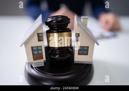 Nahaufnahme eines Richters markante Hammer zwischen Split Haus über Holz- Schreibtisch Stockfoto