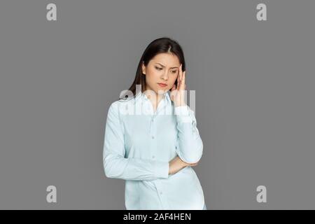 Freestyle. Junge Frau steht auf Grau holding Kopf isoliert betont Stockfoto