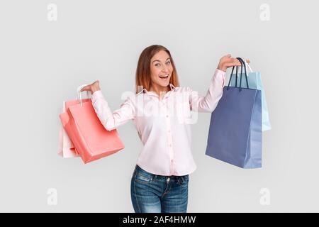 Shopping Konzept. Junge Frau steht auf Weiß mit Taschen lächelt fröhlich isoliert Stockfoto