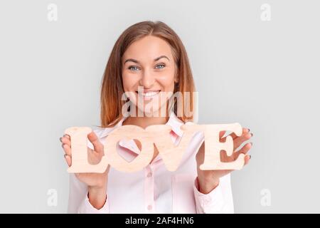 Freestyle. Junge Frau, die auf Weiß mit Liebe Zeichen lächelnd toothy Close-up isoliert Stockfoto