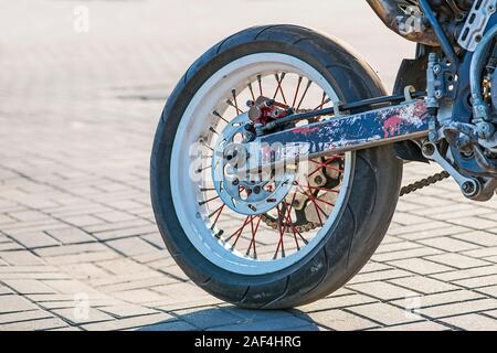 Detailansicht der hinteren Motorrad Rad und das Auspuffrohr. Hinterrad Motorrad Kettenantrieb. Stockfoto