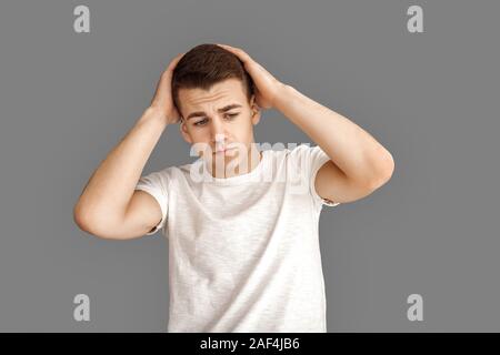 Freestyle. Junge Mann isoliert auf Grau holding Kopf umgekippt Stockfoto