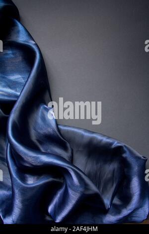 Dunkelblau Stoff falten Tüll oder Organza auf grauem Hintergrund, selektiver Fokus Stockfoto