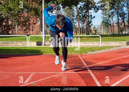 Junger Mann starten Sprint auf der Laufstrecke. Stockfoto