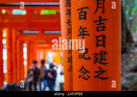 Kyoto, Japan - 24. März 2017: unkenntlich Menschen gehen unter tori Tore und in der Nähe der Japanischen Schrift am Fushimi Inari Schrein, auf Stockfoto