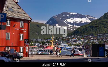 TROMSØ, NORWEGEN - Menschen zu Fuß am Hafen mit Bergen in der Ferne. Stockfoto