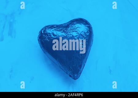 Herz Schokolade in Folie. Valentinstag Konzept, Flach, Kopieren spase. Die PANTONE-Farbe des Jahres 2020 Classic Blau Stockfoto