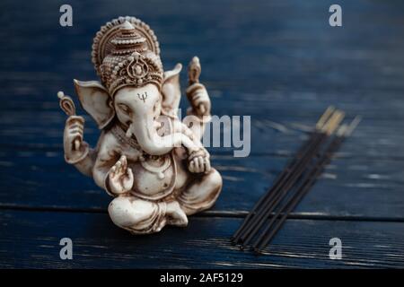 Hindu Gott Ganesh auf schwarzem Holz- Hintergrund. Statue auf Tabelle mit Sandelholz stick schließen oben mit Platz für Text kopieren Stockfoto