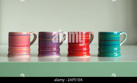 Set von vier kleinen bunten Tassen Kaffee in einer Reihe angeordnet. Pink, Lila, Rot, Blau. Stockfoto