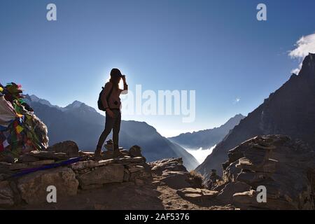 Silhouette der westlichen Frau, die auf einem Berg in Nepal mit klaren blauen Himmel Stockfoto
