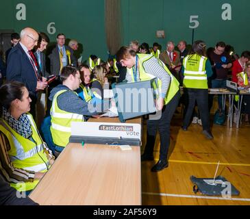 Meadowmill Sports Centre, East Lothian, Schottland, Vereinigtes Königreich, 13. Dezember 2019. Bundestagswahl: Die Zahl der Stimmen für die East Lothian Wahlkreis. Im Bild: Die ersten Urnen werden gezählt Stockfoto