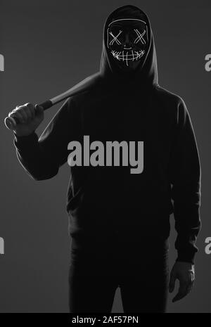 Porträt eines anonymen kriminellen Mann mit Baseballschläger in einer schwarzen Kapuze sein Gesicht hinter einer Maske. Studio gedreht. Stockfoto