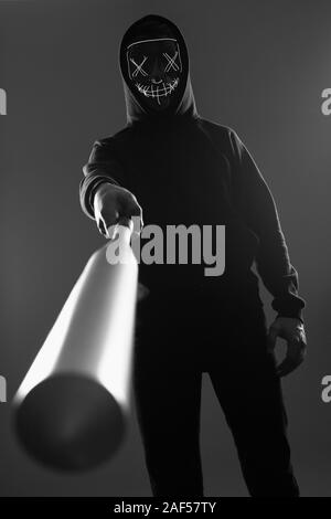 Porträt eines anonymen kriminellen Mann mit Baseballschläger in einer schwarzen Kapuze sein Gesicht hinter einer Maske. Unterer Winkel Stockfoto