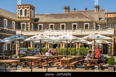 Melbourne, Australien - 17. November 2009: Belgisches Bier Café Blaustein. Bier Innenhof als Garten mit Menschen an Tischen mit Sonnenschirmen unter blauem Himmel. Uhr Stockfoto