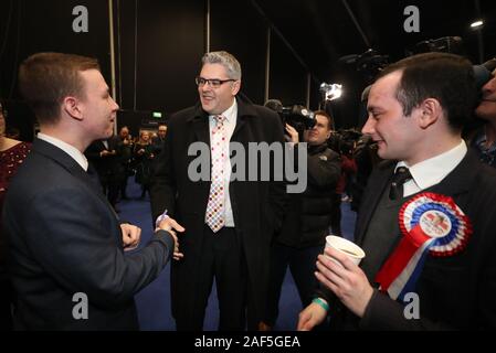 DUP Kandidat für den Osten Belfast Gavin Robinson (Mitte) trifft als die Zählung im Titanic Exhibition Center, Belfast fährt fort, für die Bundestagswahl 2019. Stockfoto