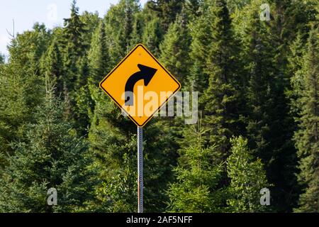 Warnung für eine Kurve nach rechts, leicht verbiegen oder Kurve in der Straße vor, Warnung Verkehrszeichen, in selektiven Fokus Ansicht mit Waldbäumen Hintergrund Stockfoto