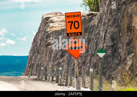 Temporärer Zustand schildern, ein orangefarbenes Zeichen zeigt die maximale sichere Geschwindigkeit ist 70 km mit Bump oder unebenen Pflaster auf der Straße am Straßenrand Stockfoto