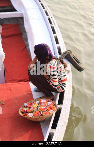 Ein Mädchen sitzt auf dem Boot mit einem Korb voller Blumen Stockfoto