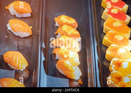 Reihen von japanischen Sushi essen. Maki ands Brötchen mit Thunfisch, Lachs, Garnelen, Krabben und Avocado. Blick von oben auf die sortierten Sushi in schwarzem Kunststoff Behälter, Stockfoto