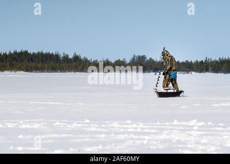 Bohren eine Loch auf einem zugefrorenen See mit einer Schnecke macht Eis-Fischer Stockfoto