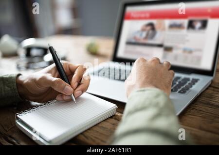 In der Nähe von einem Geschäftsmann Hand schreiben Hinweis Mit Pen im Tagebuch über Schreibtisch Stockfoto