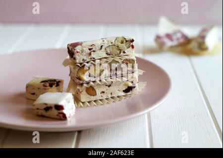 Nahaufnahme des Soft Nougat mit Beeren auf einem Teller mit Weihnachtsschmuck. Weißer Hintergrund Stockfoto