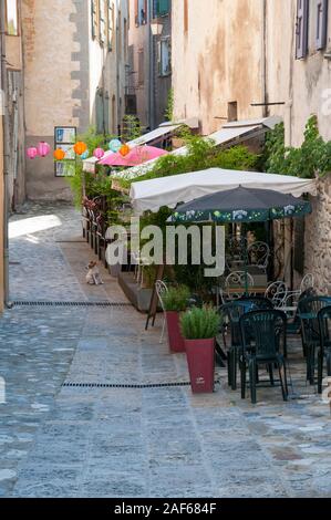 Terrasse von einem lokalen Restaurant/Bar in einer Gasse des mittelalterlichen Dorfes von Entrevaux, Alpes-de-Haute-Provence (04), Provence, Frankreich Stockfoto