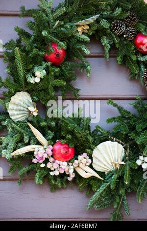 Natürliche immergrünen Kranz mit austernschalen, granatäpfel eingerichtet, Tannenzapfen, getrockneten Okra und kleinen weißen und rosa Blüten. Colonial Williamsburg. Stockfoto