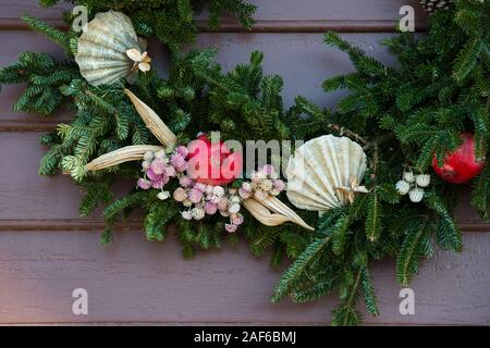 Nahaufnahme. Immergrünen Kranz mit austernschalen, granatäpfel eingerichtet, Tannenzapfen, getrockneten Okra und kleinen weißen und rosa Blüten. Colonial Williamsburg. Stockfoto