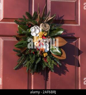 Immergrünen Kranz mit austernschalen, Magnolia Blätter, rote Paprika, Bird Nest eingerichtet, Tannenzapfen, getrockneten Okra und roten Beeren. Colonial Williamsburg. Stockfoto