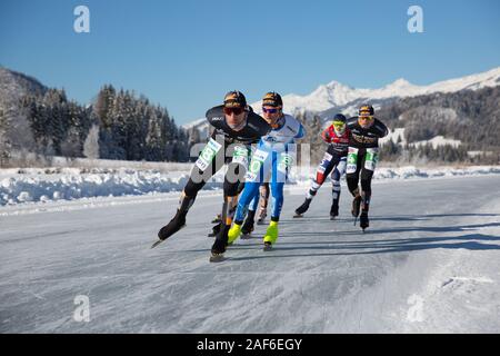 Schlittschuhlaufen auf dem See, in einem schönen Winterlandschaft. Gruppe von Männern Meisterschaft Marathon Ice Speed-Skating auf Natureis, Weissensee, Österreich Stockfoto