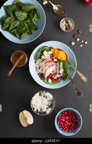 Eine Schüssel mit gesunden Lebensmitteln. Früchte mit Spinat und Frischkäse sind gewürzt mit Honig und Nüssen. Ökologische Lebensmittel. Stockfoto