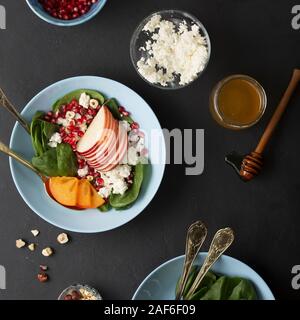 Eine Schüssel mit gesunden Lebensmitteln. Früchte mit Spinat und Frischkäse sind gewürzt mit Honig und Nüssen. Ökologische Lebensmittel. Stockfoto