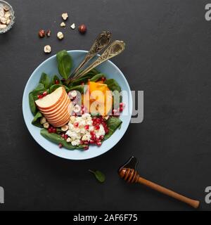 Eine Schüssel mit gesunden Lebensmitteln. Früchte mit Spinat und Frischkäse sind gewürzt mit Honig und Nüssen. Ökologische Lebensmittel. Stockfoto