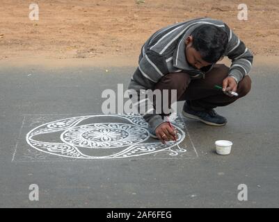 Durgapur, Westbengalen/Indien - Dezember 08,2019. Ein nicht identifiziertes Indischen männlichen Artisan mit Pinsel Zeichnung Alpona auf der Straße. Stockfoto