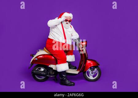 Voller Körper Foto von santa claus Mann kam Neujahr Party mit dem Fahrrad in Stupor wenige Leute tragen Sun specs Hose hat rote Hosenträger isoliert Lila Stockfoto