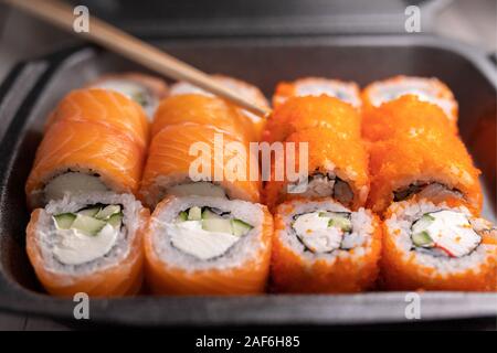 Klassische Brötchen mit Lachs, Reis, Seetang, Käse, Krabben und Gurke. Japanisches Essen. Snack Lieferung an der Arbeit und zu Hause. Stockfoto