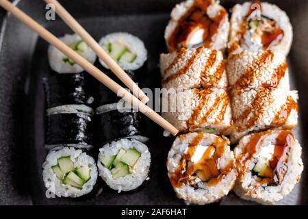 Sushi Set Rollen in der Kunststoff Lieferung Essen mit Stäbchen. Ansicht von oben. Japan Menü Stockfoto