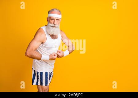 Foto von Ernst zuversichtlich attraktiver reifer Mann demonstriert seine Trizeps stehend drehte sich in der Nähe der leeren Raum isoliert leuchtend gelben Farbe Hintergrund Stockfoto