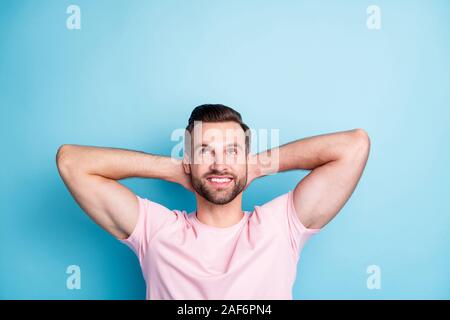 Foto von attraktiven Kerl, Hände hinter dem Kopf genießen Sie tolles Wochenende die Suche nach leeren Raum Träumer Verschleiß casual Rosa t-shirt isoliert Blau Stockfoto