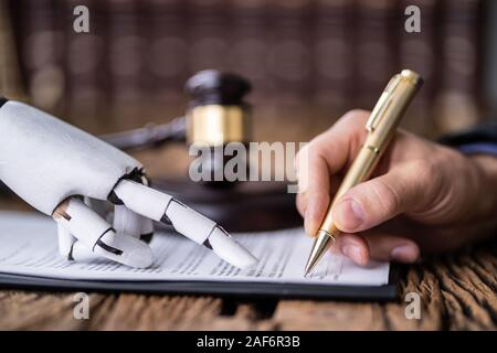 Roboterhand Unterstützung der Person, die für die Unterzeichnung dieses Dokuments Holzschreibtisch im Gerichtssaal Stockfoto
