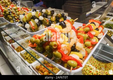 Grüne Oliven und Garnelen auf Holzstäbchen zum Verkauf an Mercado Markt San Miguel in Madrid, Spanien Stockfoto